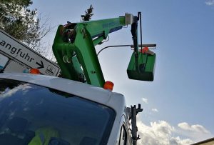 Monteur im Steiger beim Austauschen der Leuchtmittel